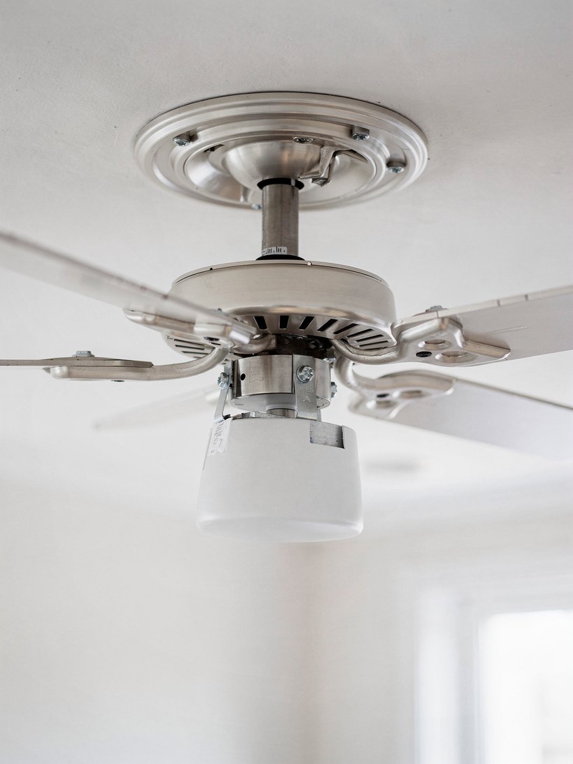 Electrician mounting a ceiling fan on a fan-rated box in Houston, TX